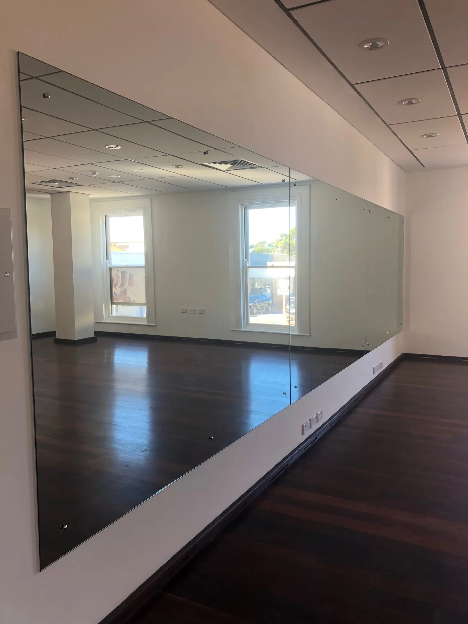 A wall of mirrors in an empty studio with timber floors