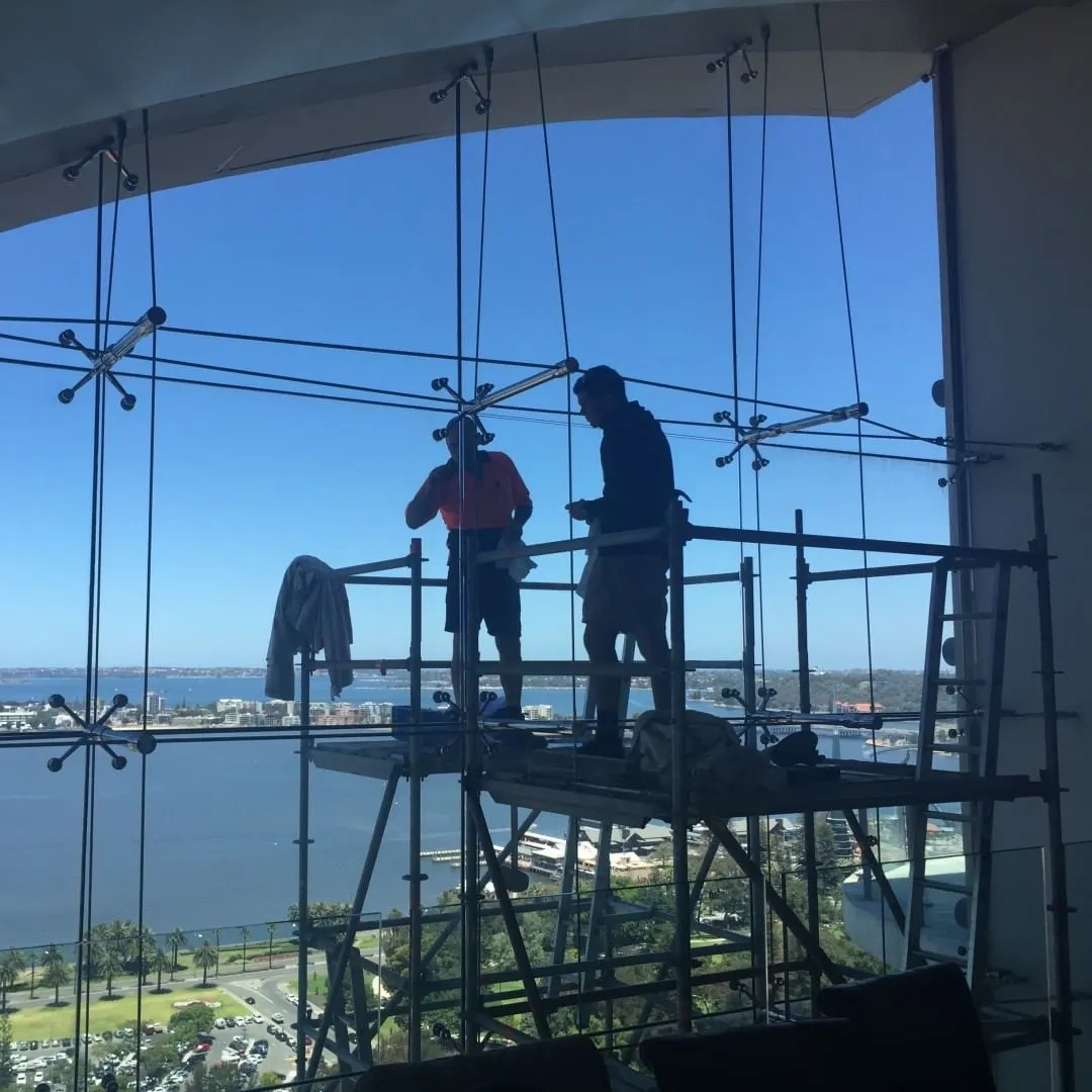 Glaziers on a scaffold fitting tall windows that look out over the river