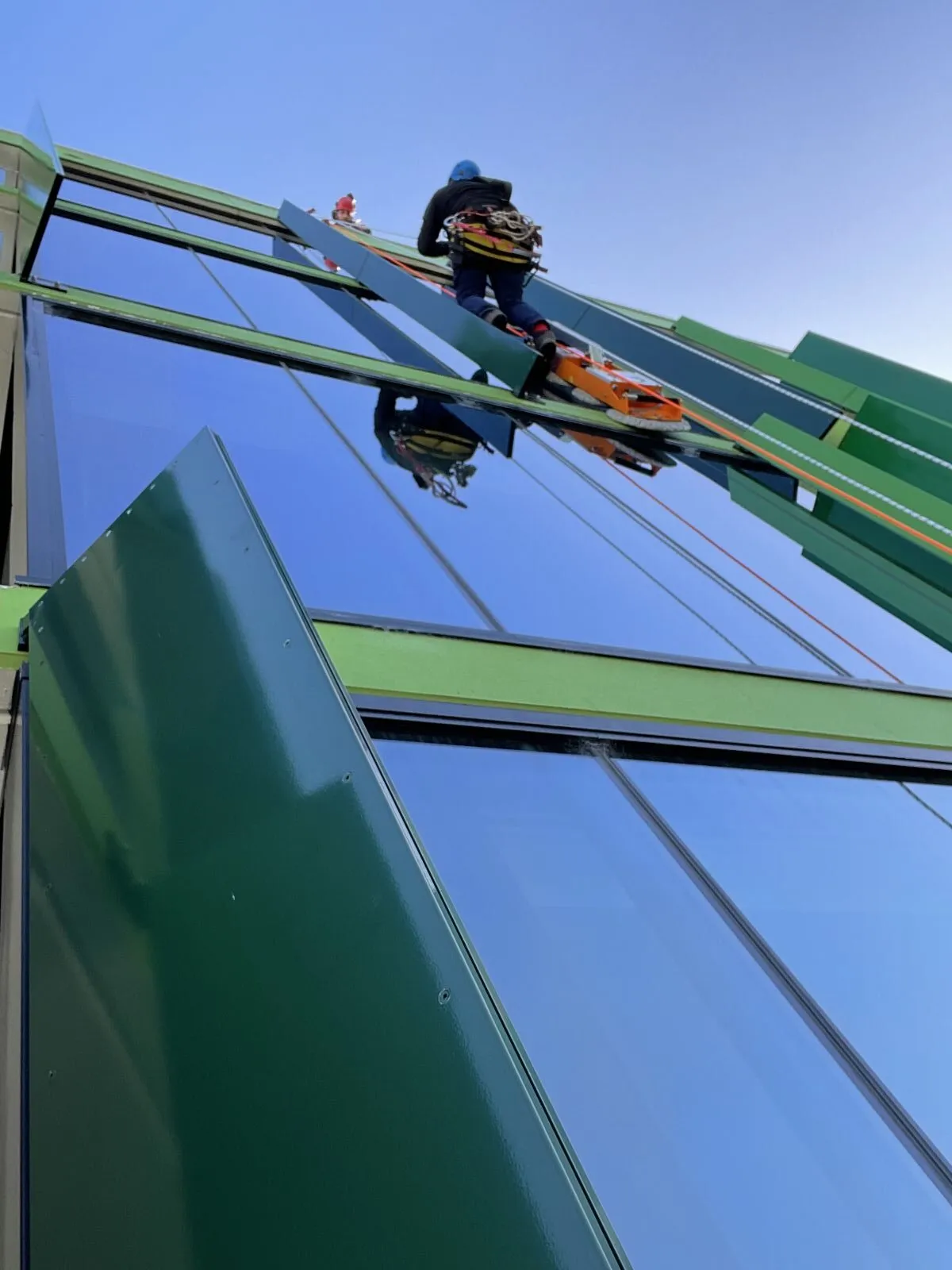 Glazier working on green framed roof glazing at height
