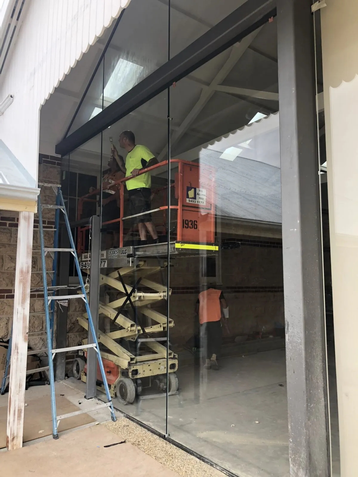 Glaziers on a scissor lift fitting a tall glass wall