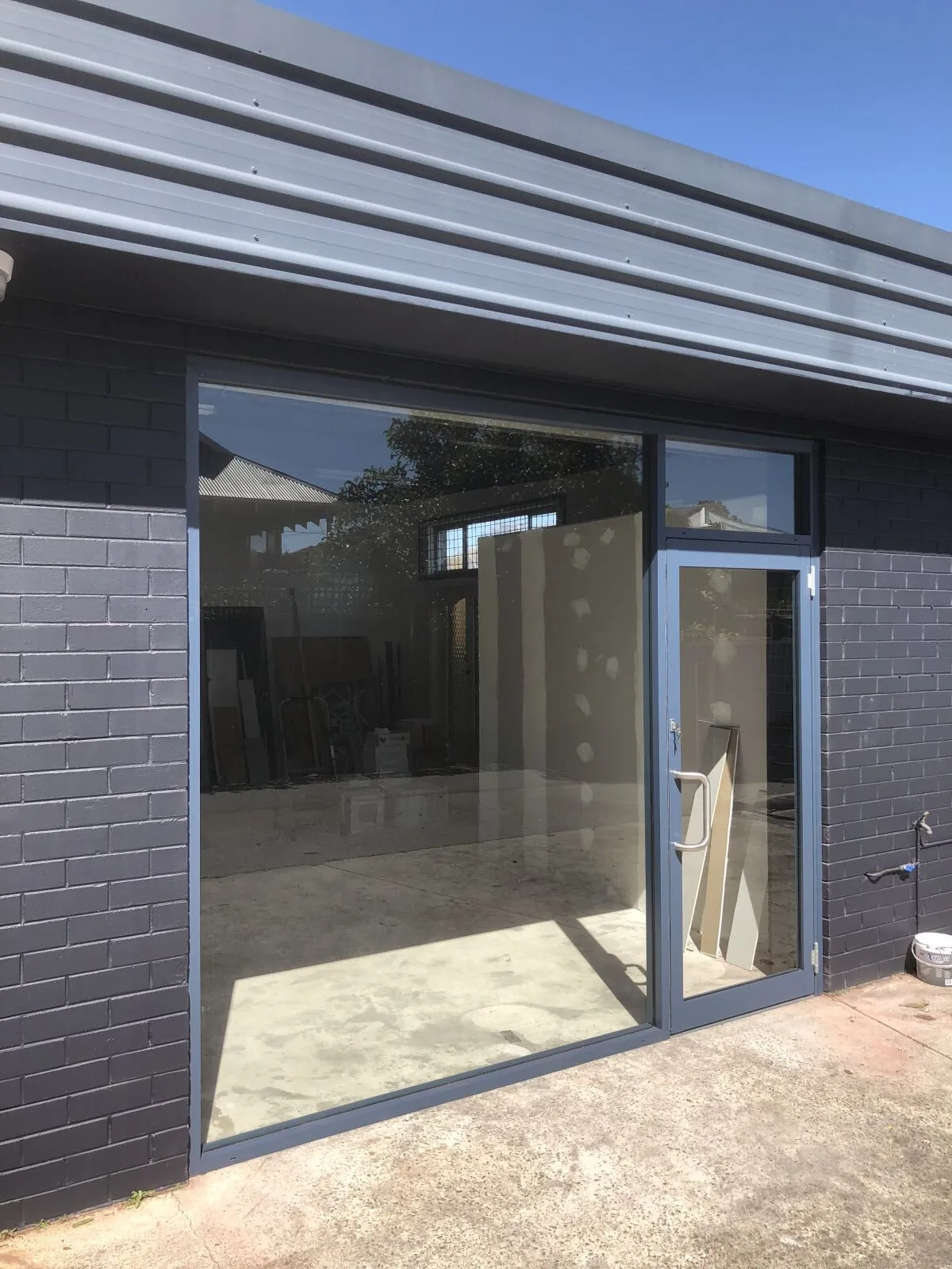 Dark framed glass door and window in a dark brick wall