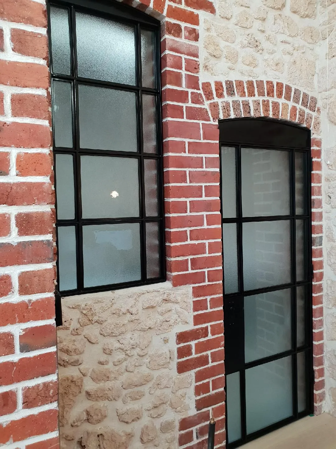 Black steel framed windows in a red brick and stone wall
