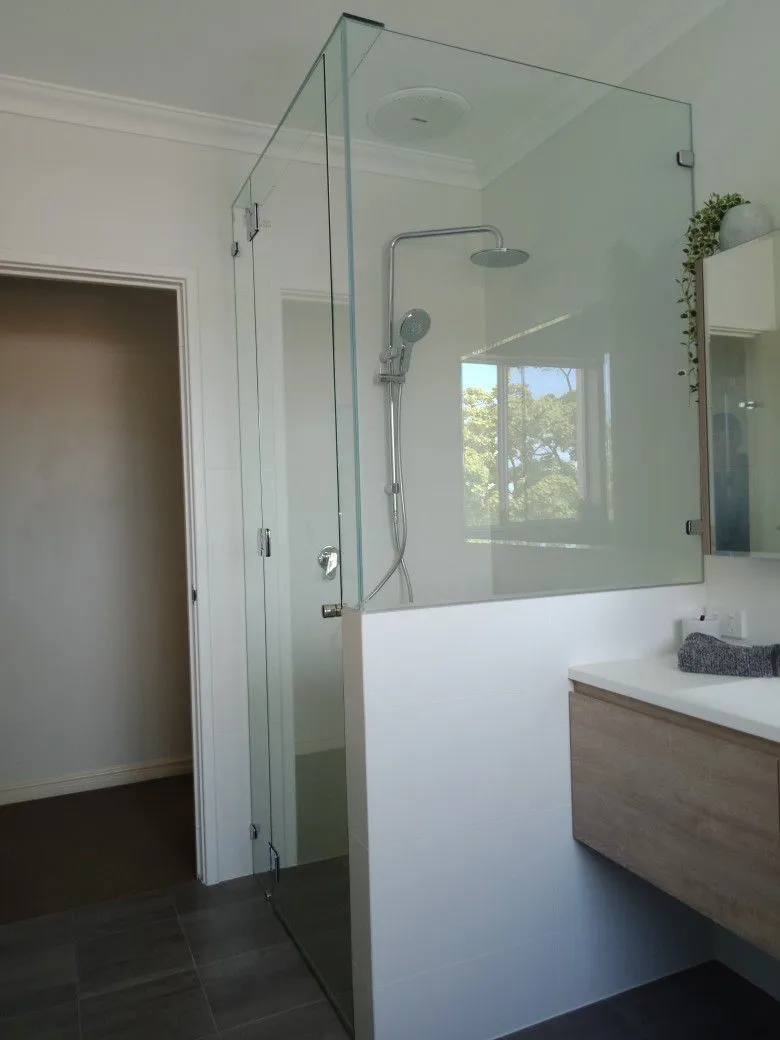 Frameless glass shower screen beside a timber vanity