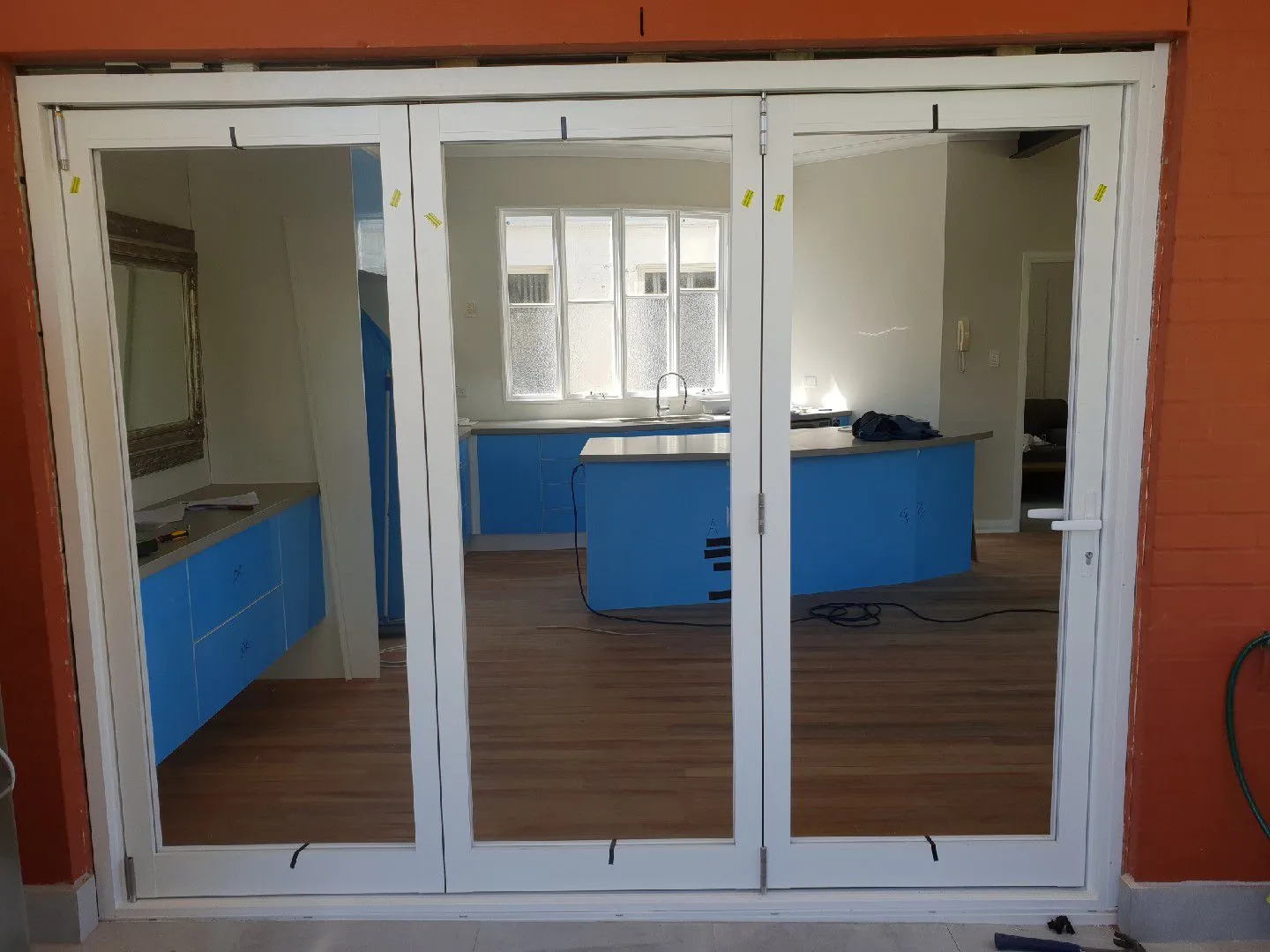 White framed bifold doors opening onto a kitchen