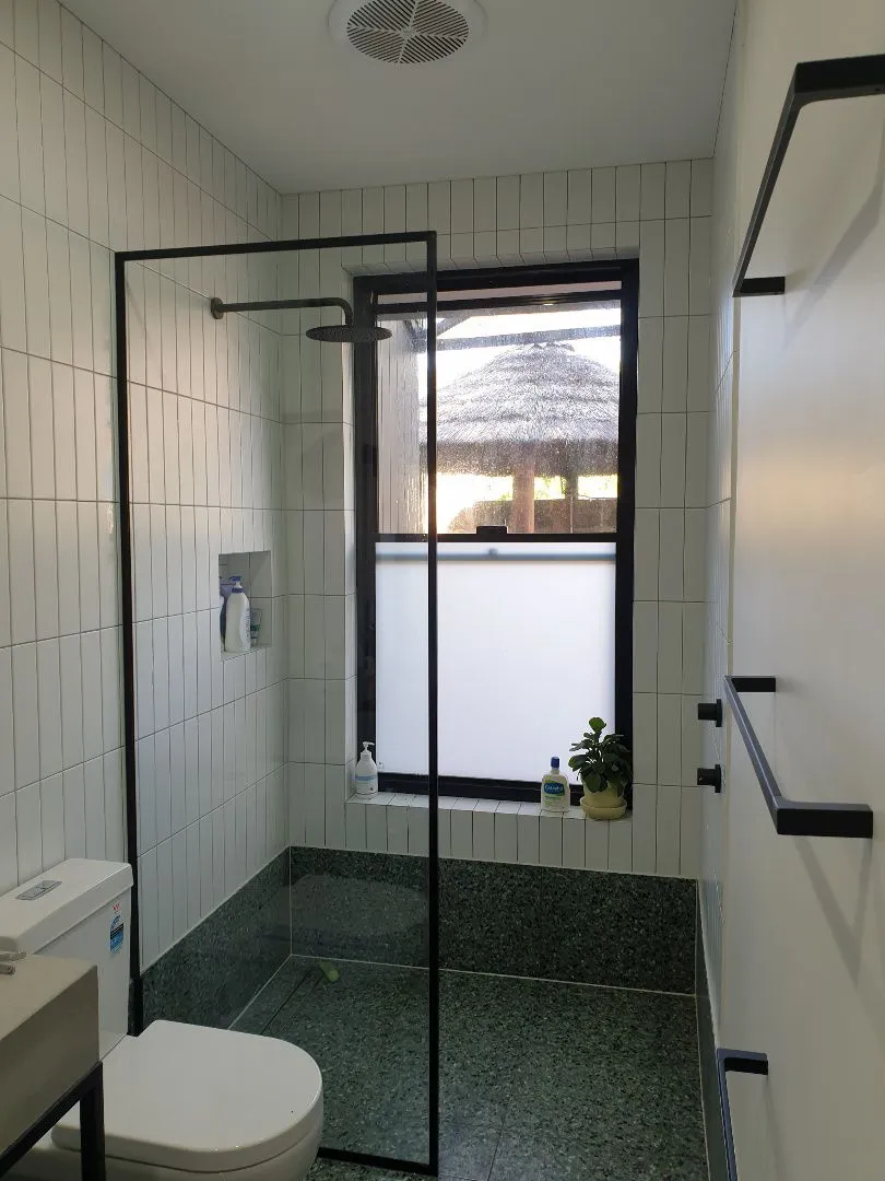 Black framed shower screen in a bathroom with a toilet