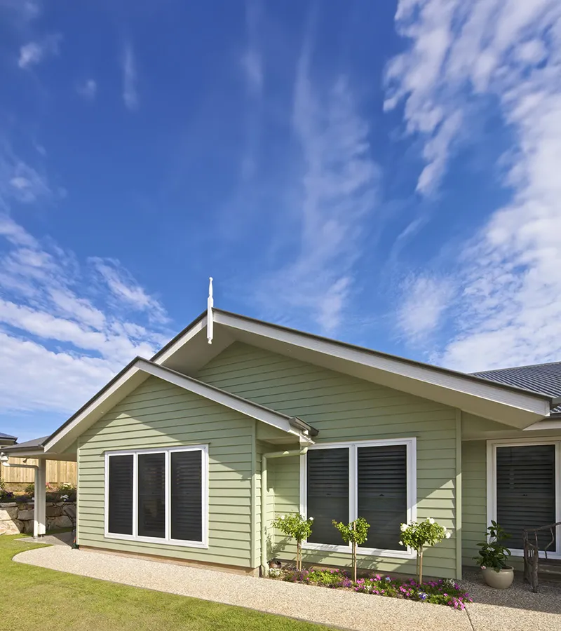 A green weatherboard home fitted with security window screens